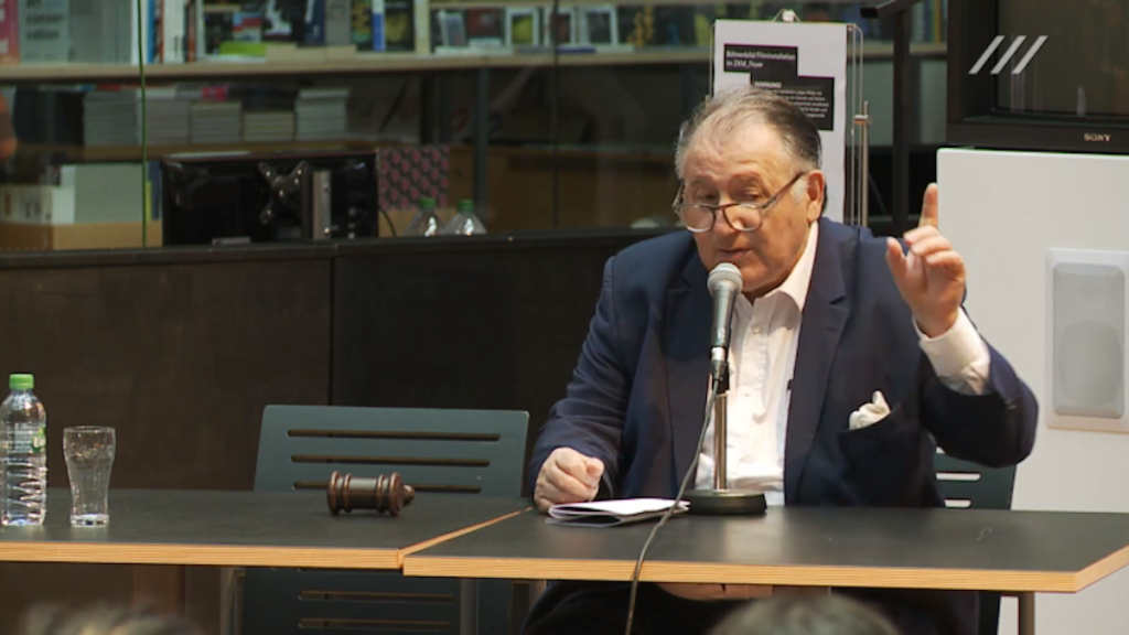 Peter Weibel, Vorstand des ZKM und konzeptioneller Leiter des Tribunals, bei der Eröffnung des zweiten Tages - neben ihm der Gerichtshammer